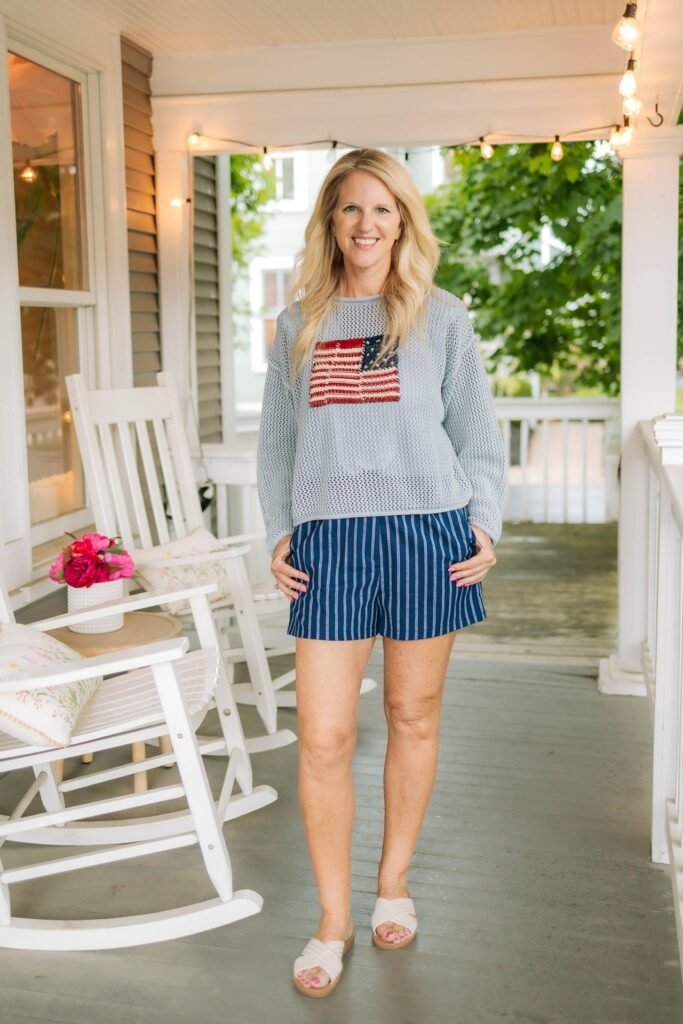 Grey Knit Sweater with American Flag Detail + Navy Blue Vertical Striped Shorts + Beige Criss-Cross Slide Sandals