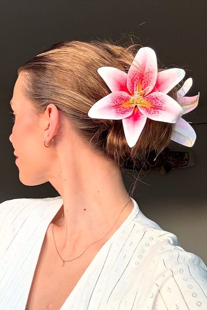 Sleek Low Bun Adorned with Oversized Pink Lily Floral Accents