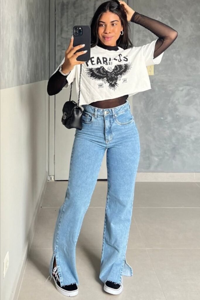 White Graphic Crop Top over Sheer Black Long-Sleeve Top + Light Blue Split-Hem Jeans + Black and White Sneakers