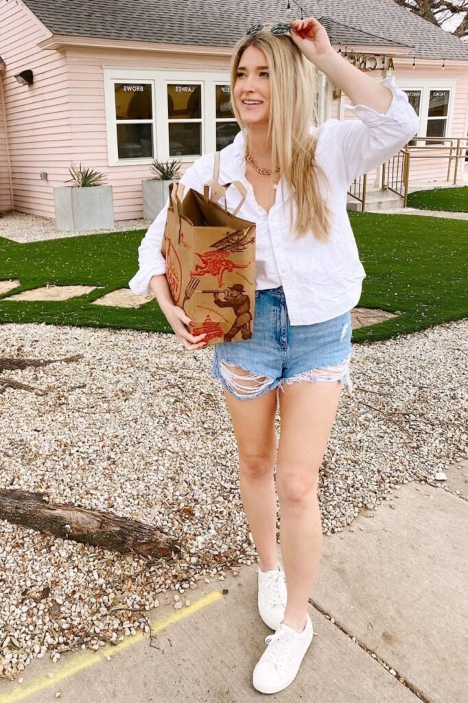 White Oversized Button-Down Shirt + Light Wash Ripped Denim Shorts + White Canvas Sneakers