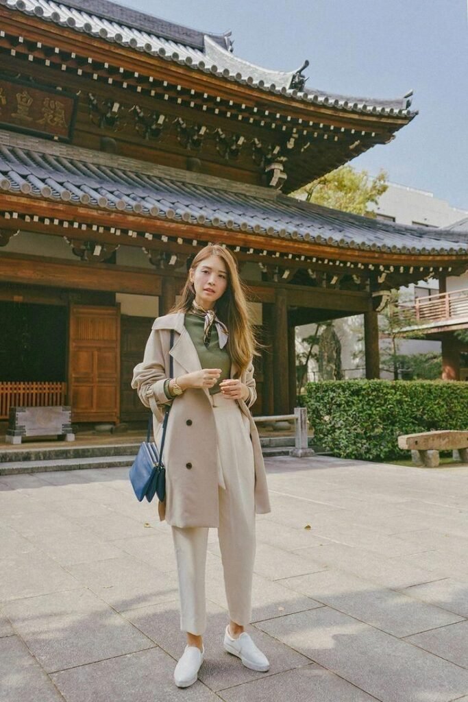 Beige Trench Coat + Olive Green High Neck Top + Beige Tapered Trousers + White Slip On Sneakers