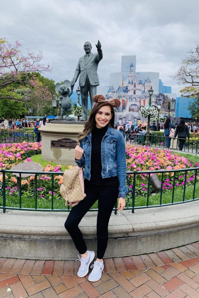 Black Mock Neck Top + Cropped Denim Jacket + Black Skinny Jeans + Grey Sneakers