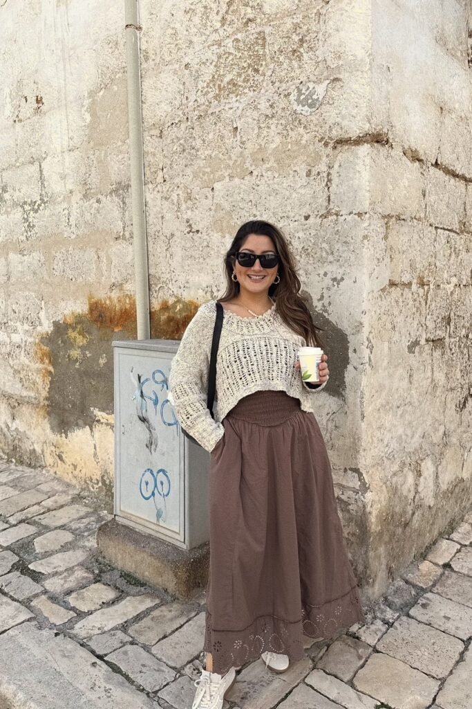 Cream Open Knit Cropped Sweater + Brown Smocked High Waisted Maxi Skirt + Black Sunglasses + Black Shoulder Bag + White Sneakers