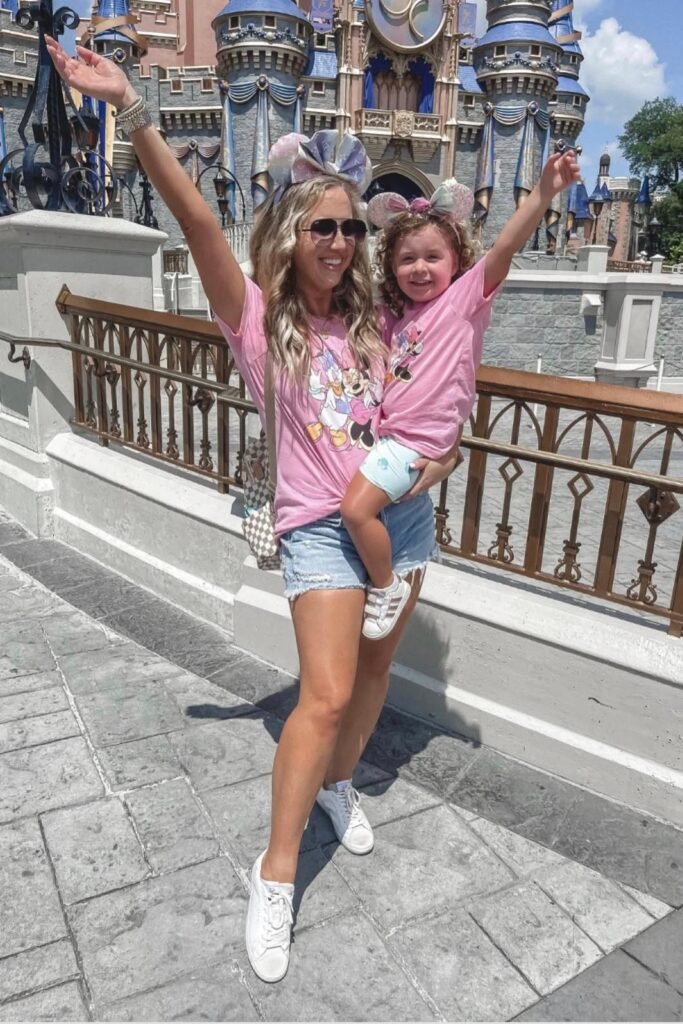 Pink Character Graphic Tee + Light Wash Distressed Denim Shorts + Checkerboard Backpack + White Sneakers