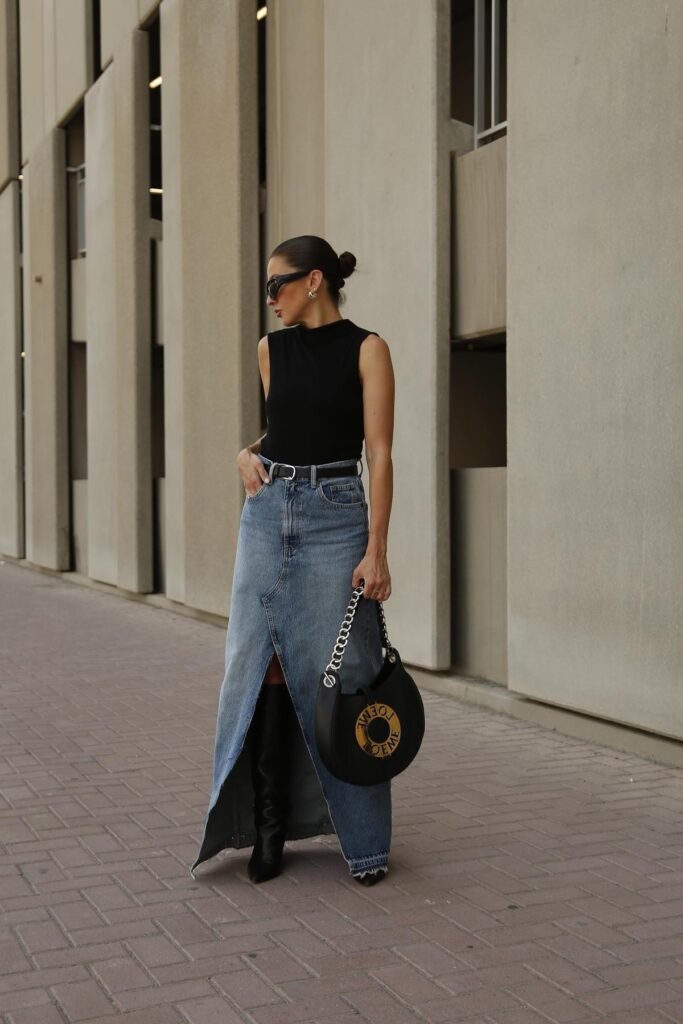 Sleeveless Black Turtleneck + Light Wash Denim Maxi Skirt with Front Slit + Black Belt + Black Knee High Boots