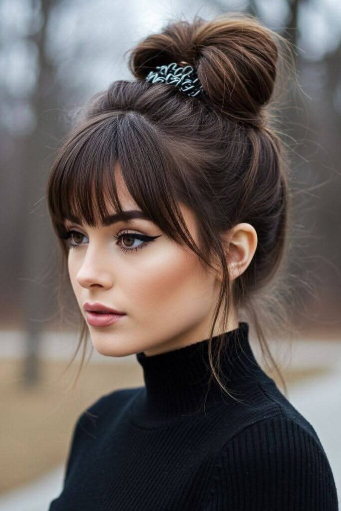High Messy Bun with Full Bangs and Face-Framing Strands